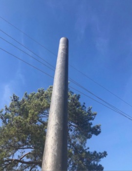 Heveatek composite utility pole prototype photographed outdoors against a blue sky